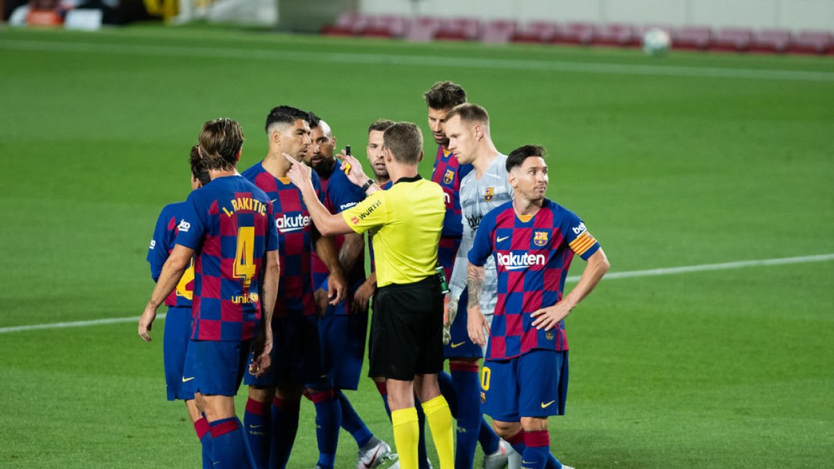 Messi mira hacia otro lado mientras sus compañeros hablan con el árbitro el martes ante el Atlético.