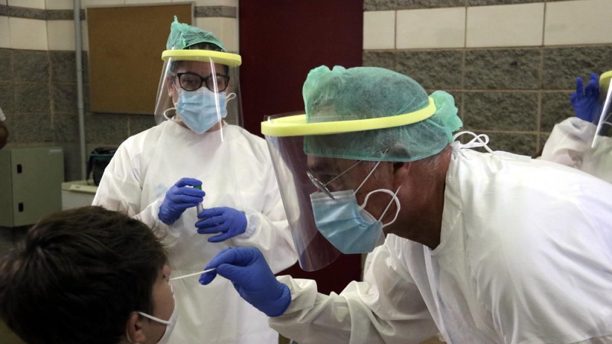 Técnicos realizan una PCR a un menor en una escuela de Girona.