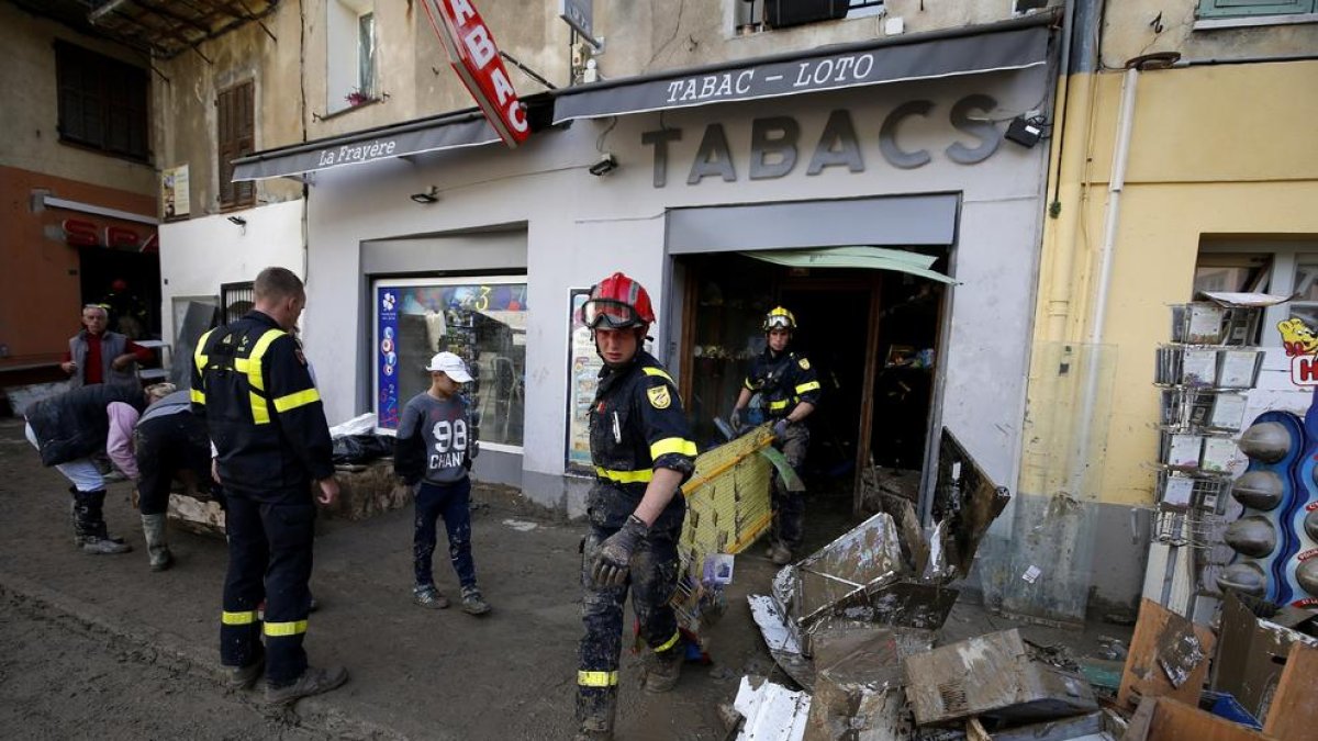 Els bombers treballen en la neteja i desallotjament de carrers i botigues després de les inundacions.