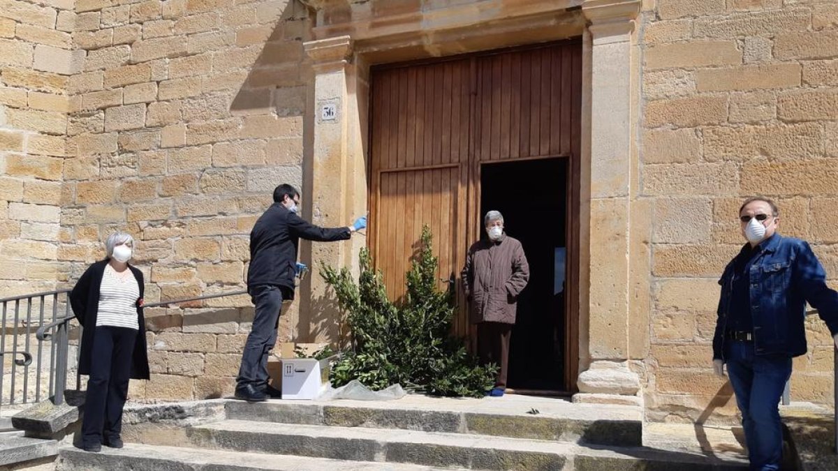 El capellà i veïns de Preixana amb mascaretes aquest diumenge durant la benedicció de rams.