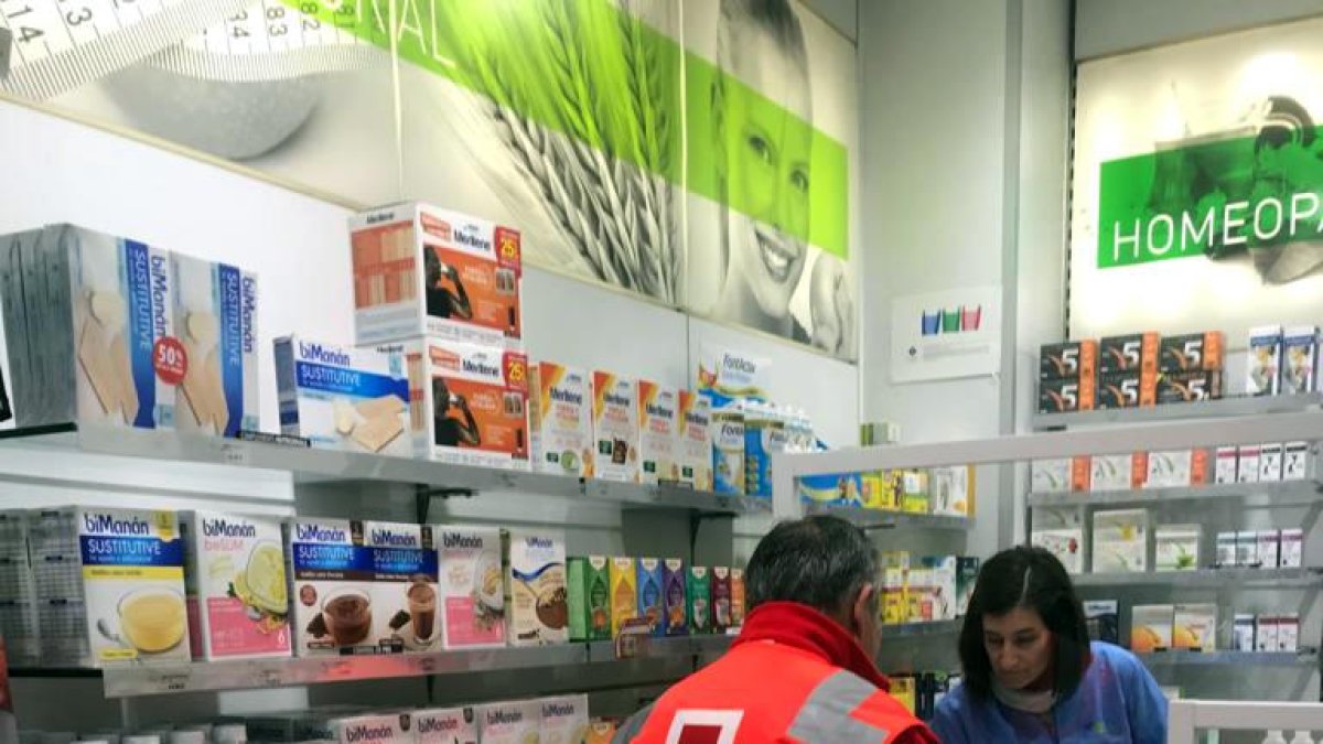 Un voluntari de Creu Roja recollint un medicament a una farmàcia de Lleida per portar-lo a un malalt.