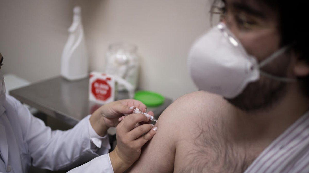 Un sanitari injecta en un voluntari una candidata a vacuna contra el coronavirus.