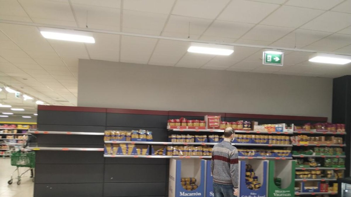 Ciudadanos haciendo cola manteniendo la distancia de seguridad delante de un supermercado en el centro urbano. 