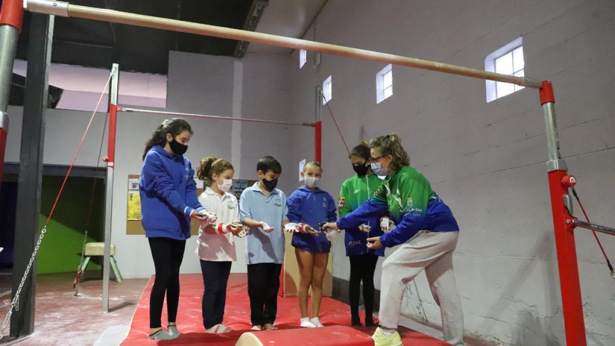 Un grupo de gimnastas del FEDAC reciben la tiza líquida de su entrenadora Maribel Moncasi ayer durante el entrenamiento.