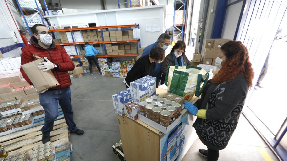 Voluntarios que ayer trabajaban preparando lotes de comida en el almacén central del Banc dels Aliments de Lleida. 