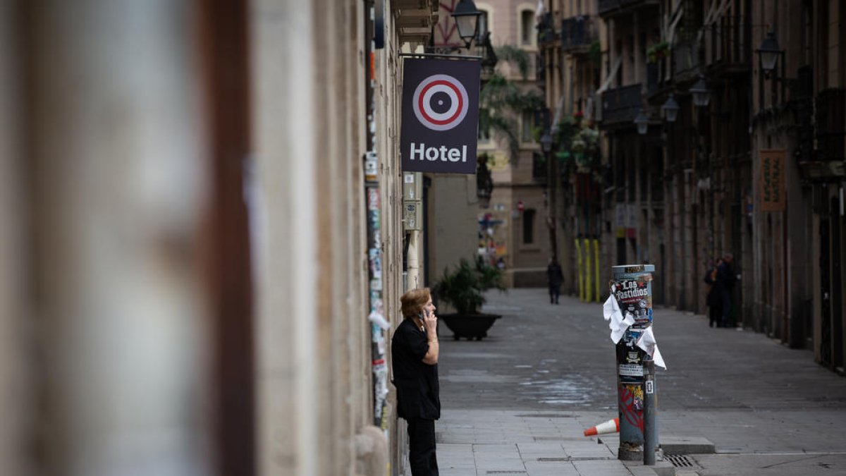 Una dona parla per telèfon en un carrer del centre de Barcelona, desert per l’ordre de confinament.