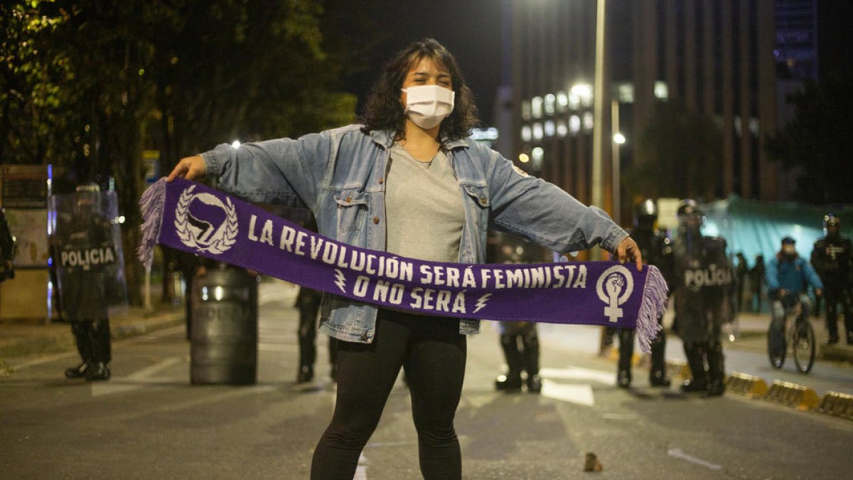 Una manifestant passa davant d’un cordó policial durant els disturbis a Bogotà.