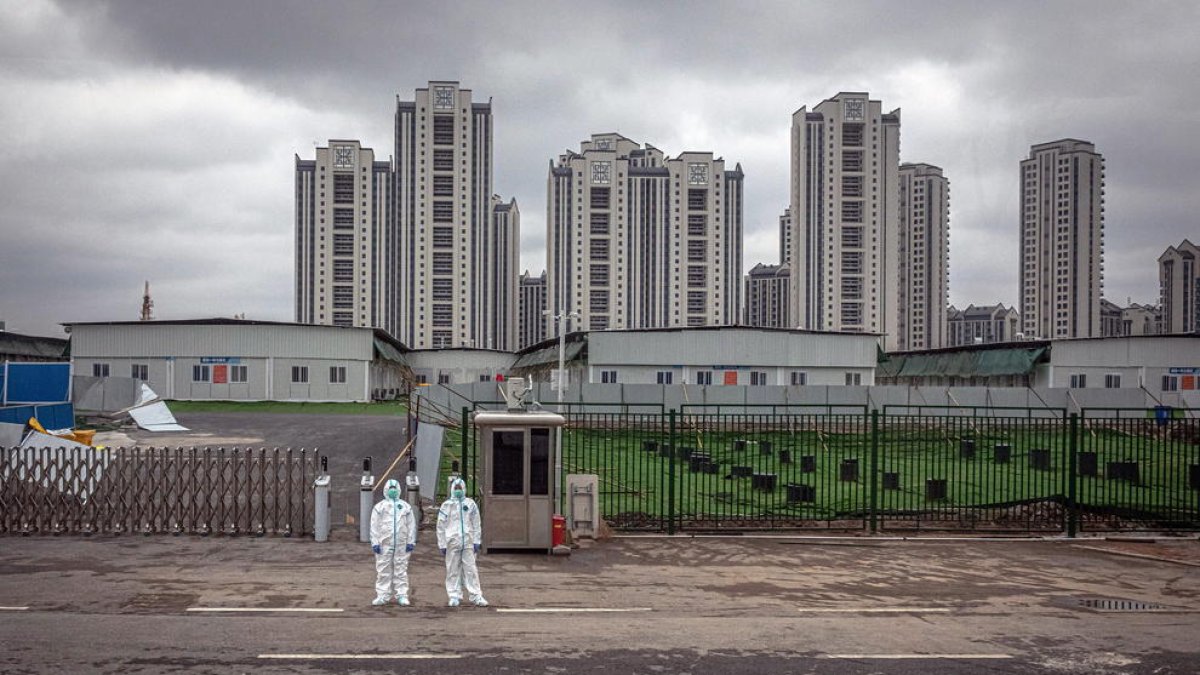 Dos vigilantes frente al hospital que China construyó en Wuhan. 