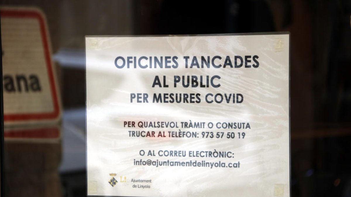Un cartell informatiu sobre la suspensió de l'atenció al públic pel brot de covid-19 a la porta de l'Ajuntament de Linyola.