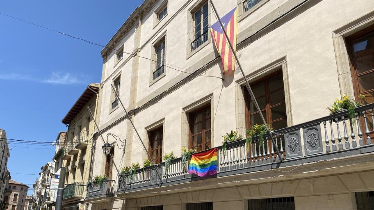 Bandera multicolor ayer en el balcón del ayuntamiento de Les Borges y fachada de la Paeria de Lleida iluminada con los colores del arco iris.