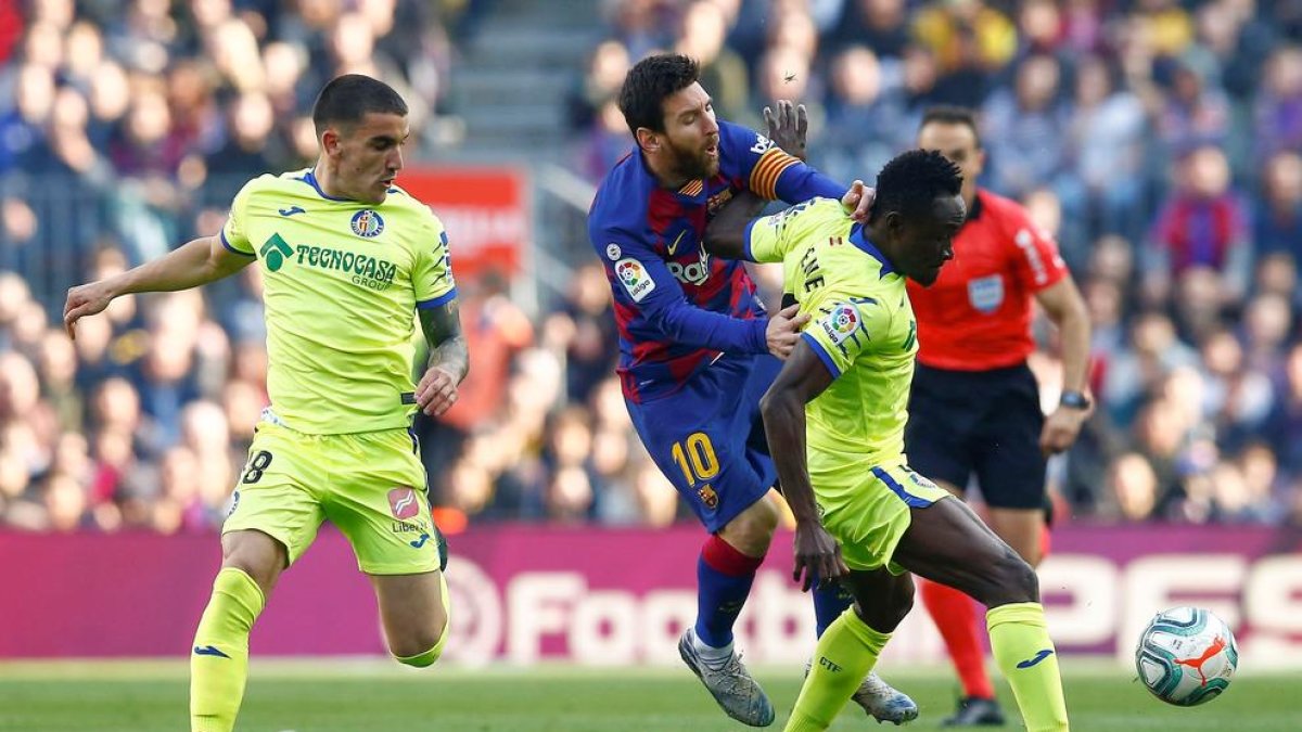 Messi es obstruido por el jugador del Getafe Etebo durante el partido de ayer en el Camp Nou.