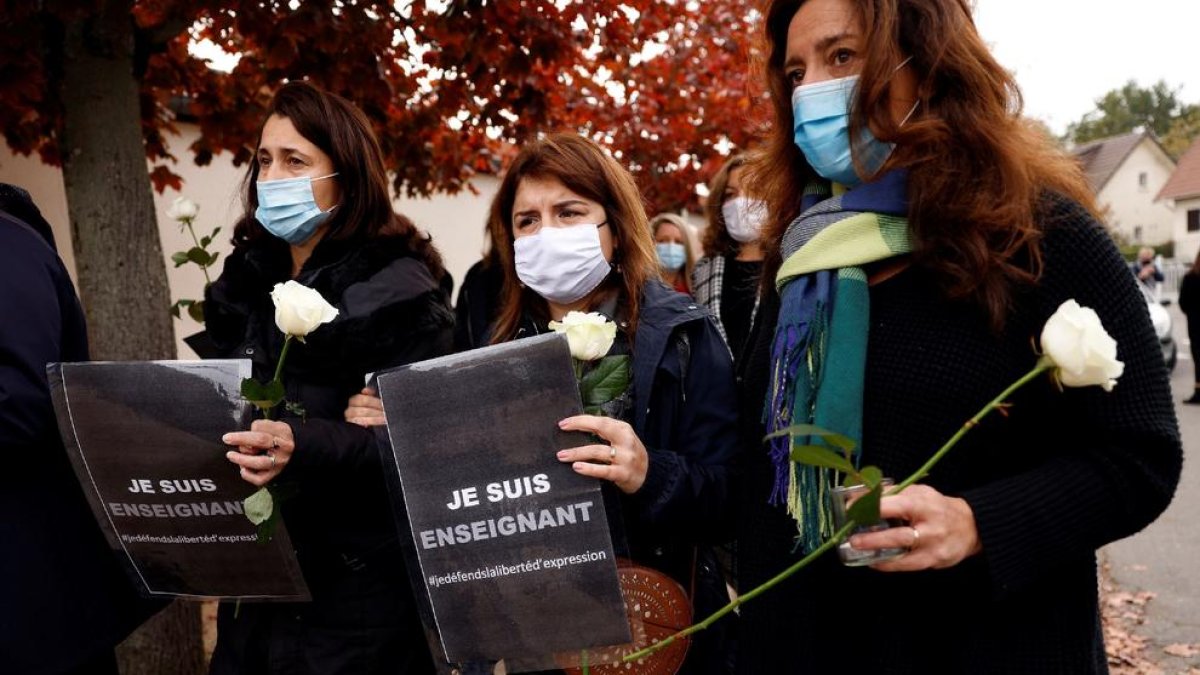 Varias compañeras del profesor asesinado portan flores para honrar a la víctima.