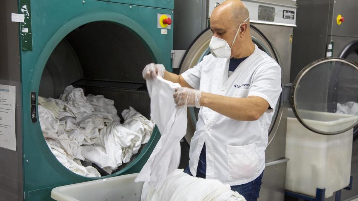 Un empleado de la lavandería del Grup Alba de Tàrrega trabajando con mascarilla y guantes.