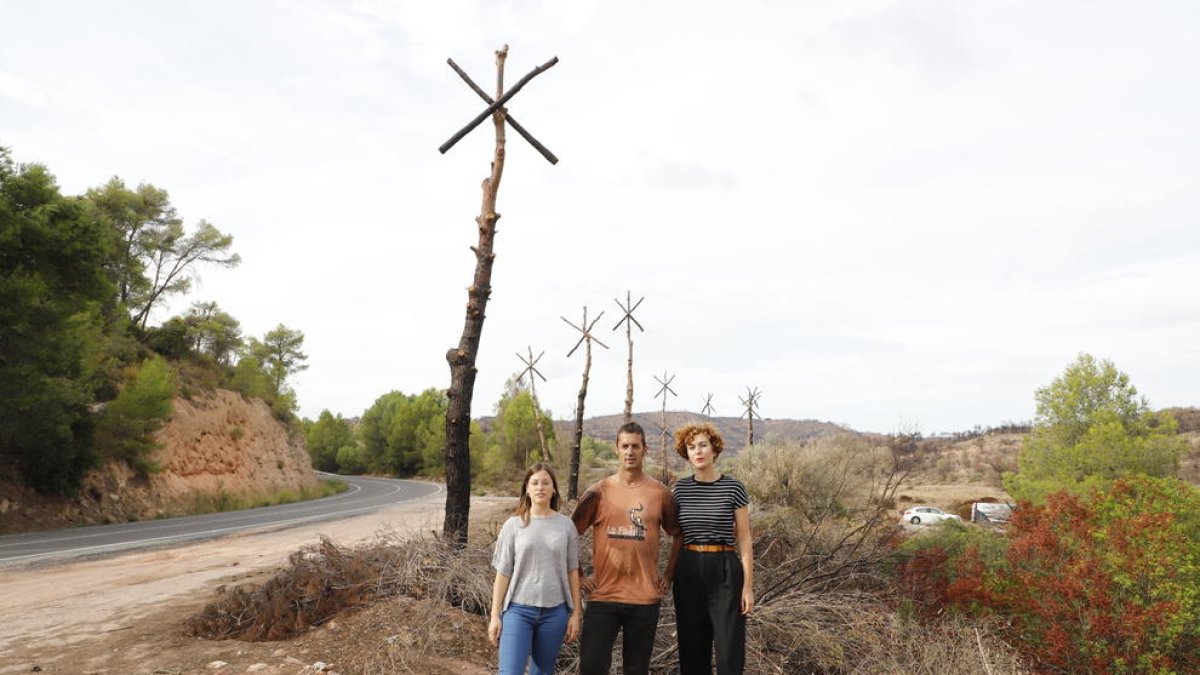 El artista Marc Sellarès y dos de las impulsaras de Camí de Cendra junto a la obra ‘Estels’ en la C-12.  