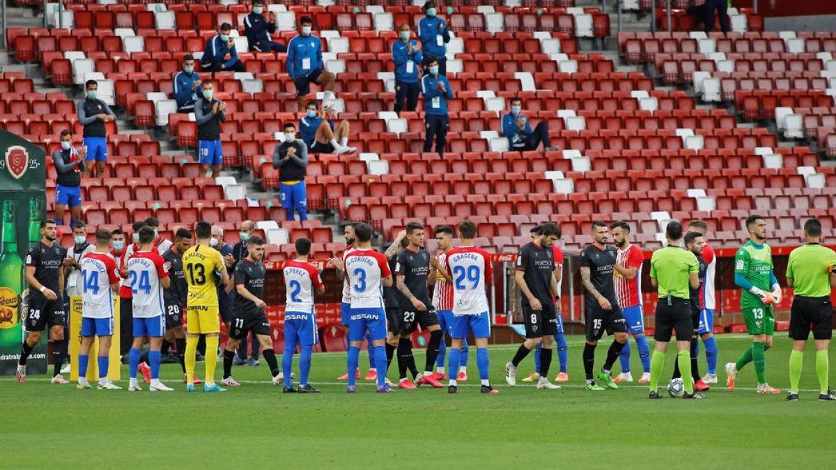 Jugadors de l’Sporting fan el passadís als de l’Osca.