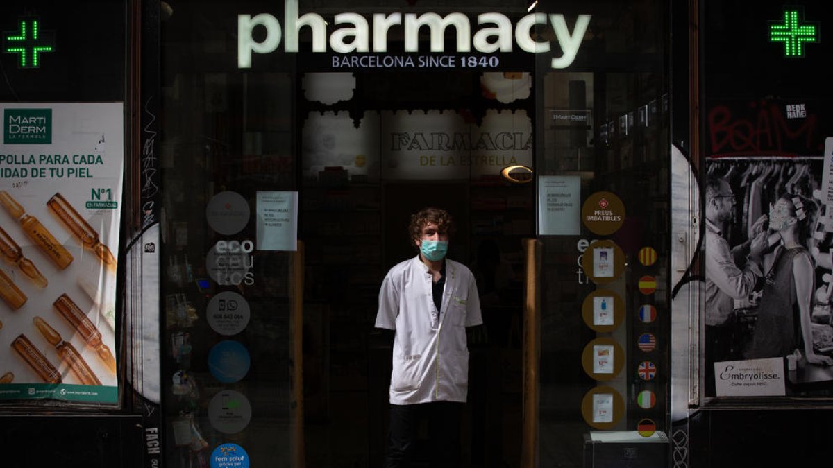 Un farmacéutico ayer a las puertas de su establecimiento en Barcelona con mascarilla.