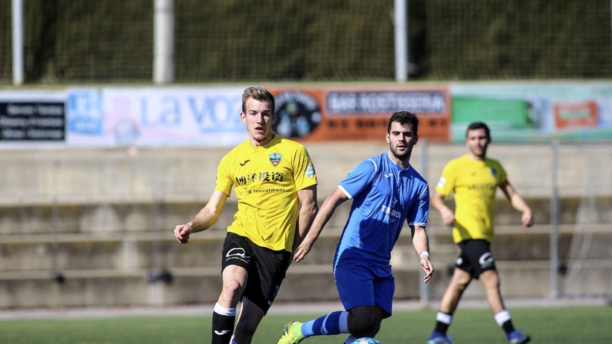 Un jugador del Lleida B conduce el balón ante la presión de un defensa rival.