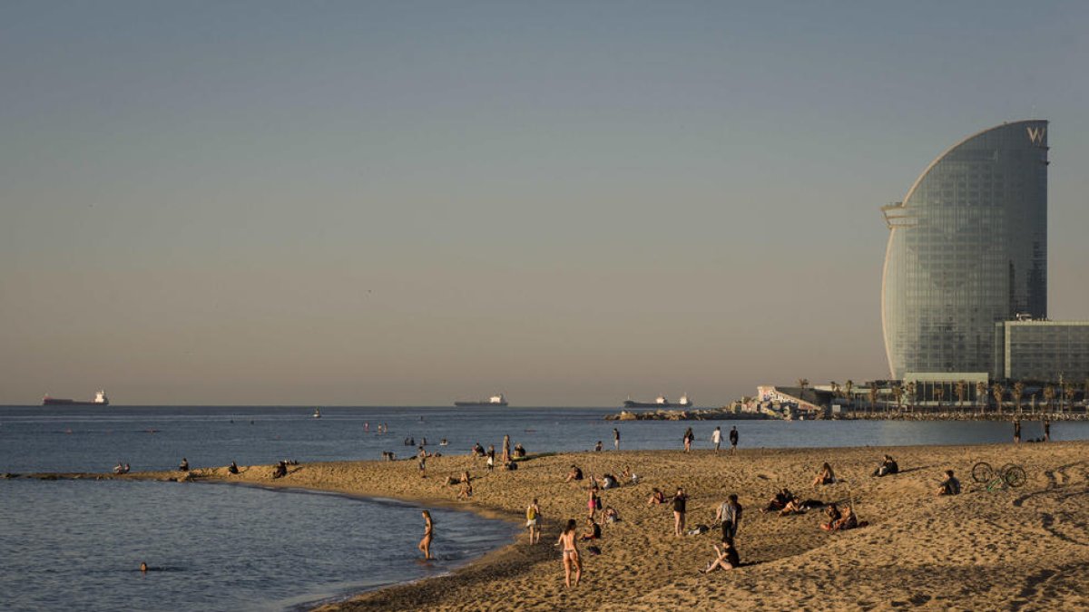 Decenas de personas a primera hora en una playa de Barcelona. Algunos toman el Sol pese a las normas.