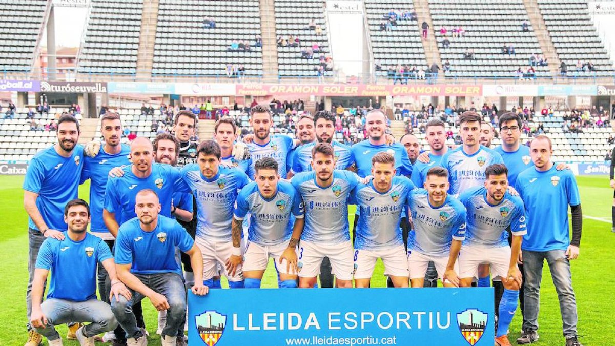 Los jugadores de un once titular del Lleida posan con aficionados antes de un partido.