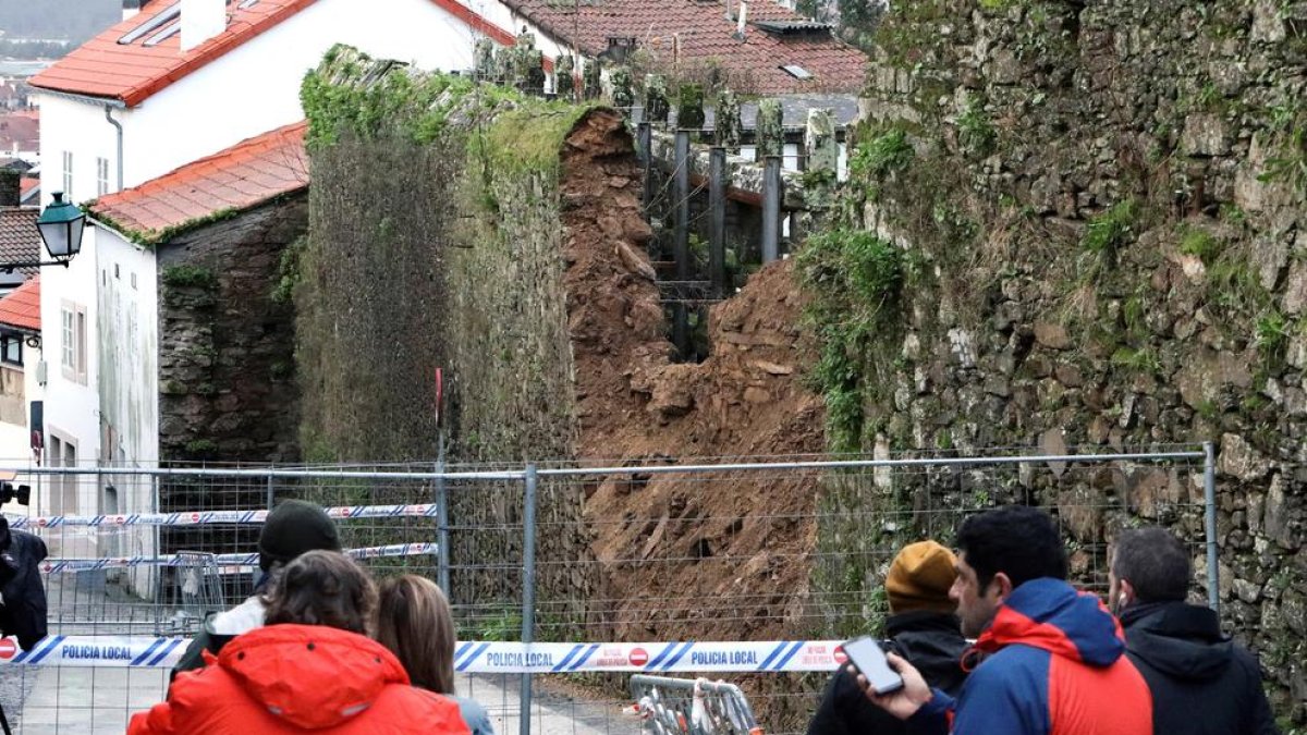 Curiosos observen el mur que va causar la mort d’un home a Santiago a l’esfondrar-se.