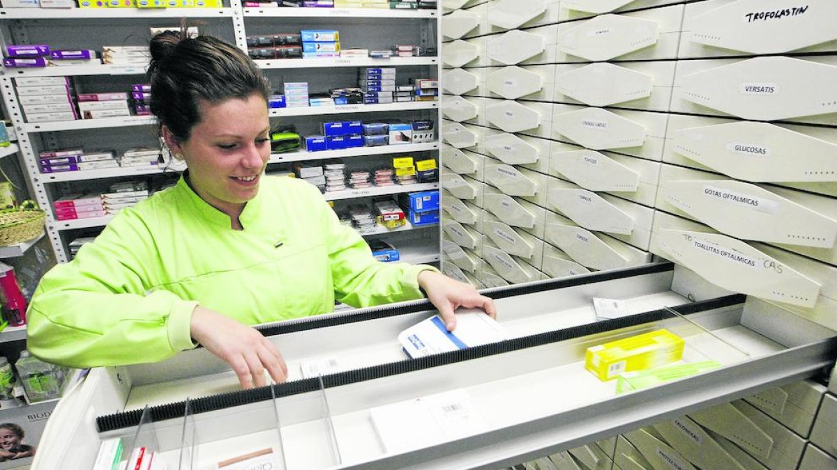Una empleada d'una farmàcia a Pardinyes mostra els calaixos buits de medecines.
