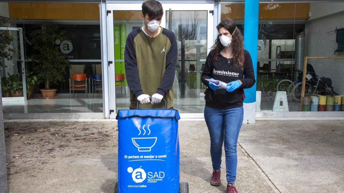 Dos voluntarios transportando la comida a domicilio. 