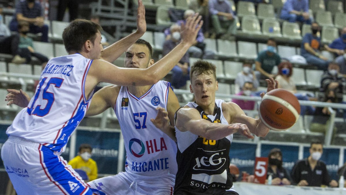 Kaspars Vecvagars suelta el balón ante la presión de dos jugadores del Alicante.