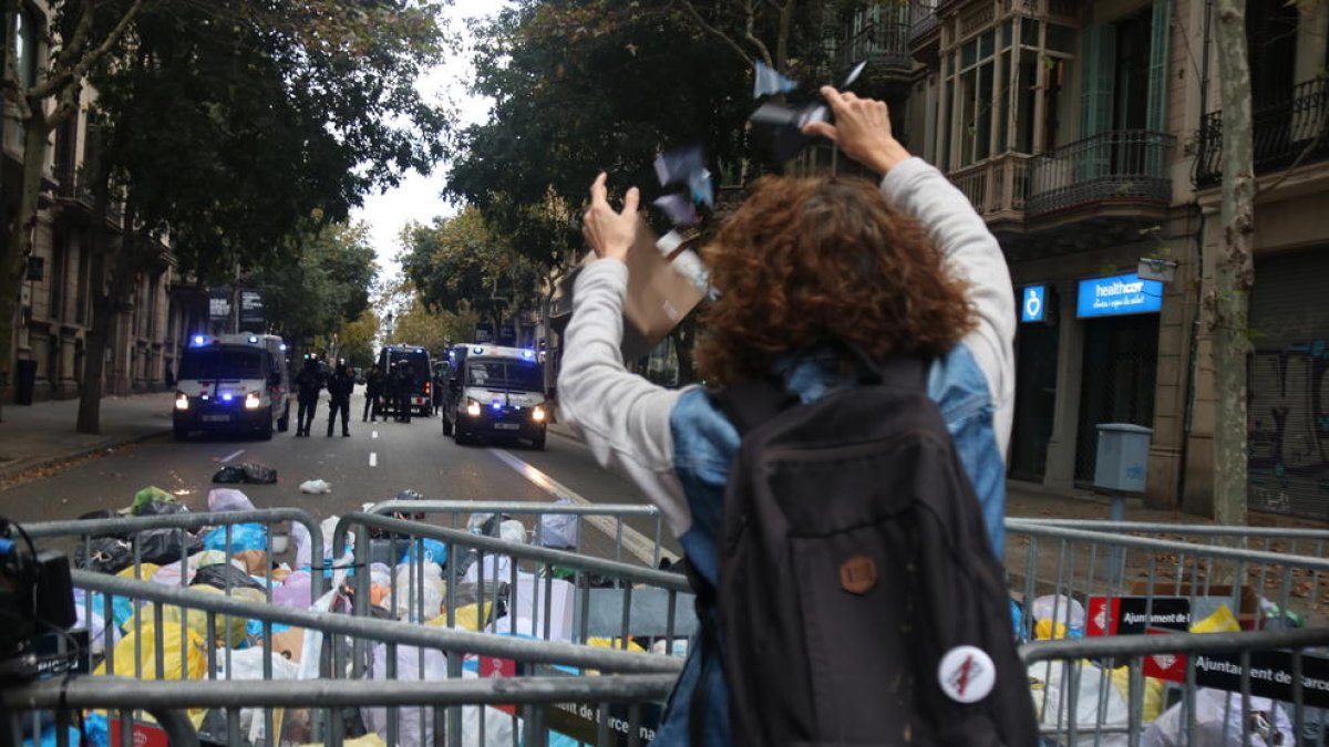 Una mujer lanza una bolsa de basura ante los Mossos.