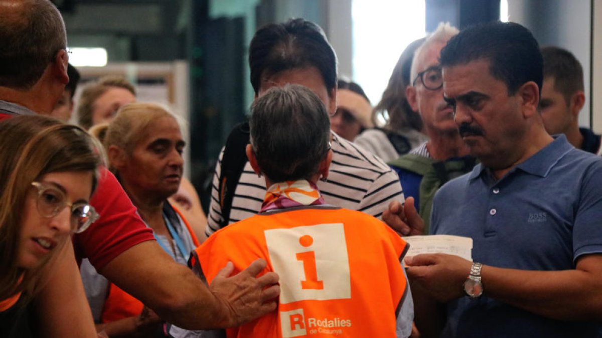 Diversos usuaris demanen informació a un empleat de Renfe.