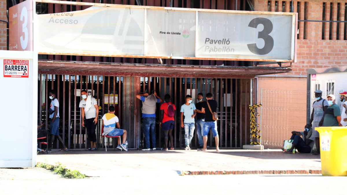 Un grupo de temporeros y sintecho espera a las puertas del pabellón 3 de la Fira para entrar, ayer. 