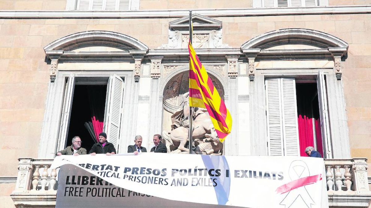 Operaris del Govern instal·lant la nova pancarta sobre l’antiga, ahir a Barcelona.