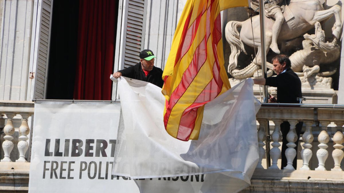 Dos treballadors de la Generalitat retiren els llaços del Palau