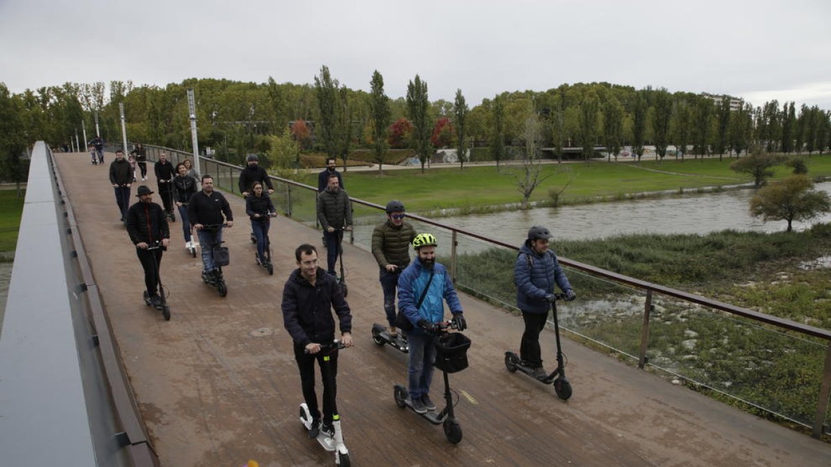 Usuaris de patinets elèctrics circulant per una passarel·la.