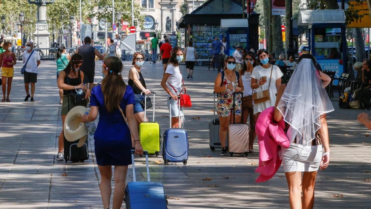 Diverses turistes caminen per la Rambla de Barcelona.