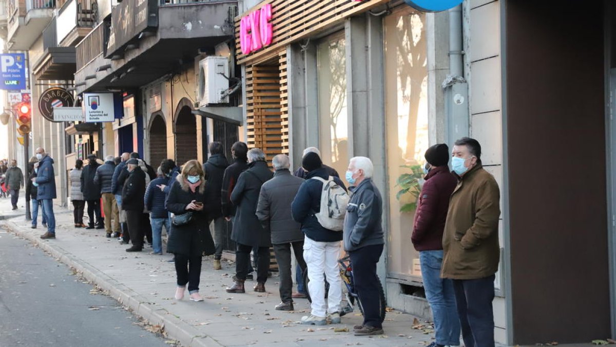Llargues cues de clients esperant per entrar en una administració de loteria a Lleida, ahir.