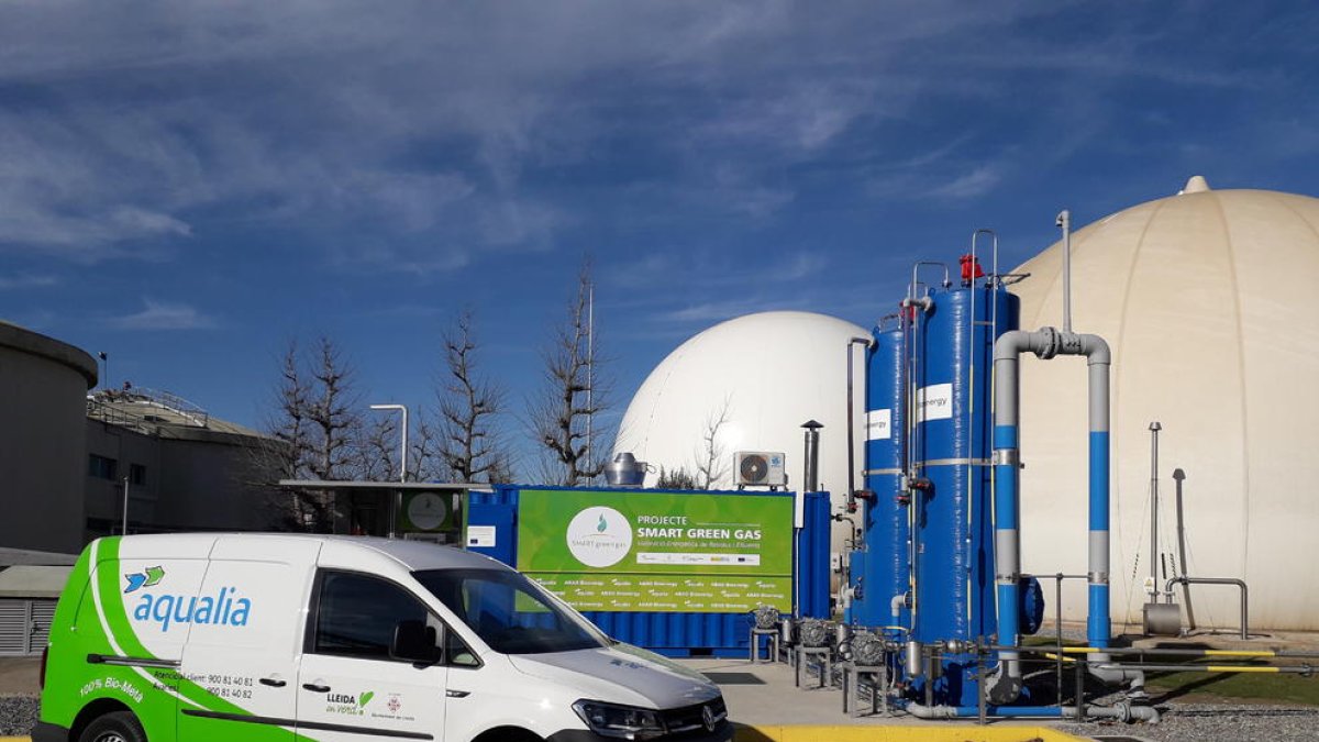 La màquina que crea el biocombustible amb el gas del llot al costat d’un vehicle que funciona gràcies a ell.