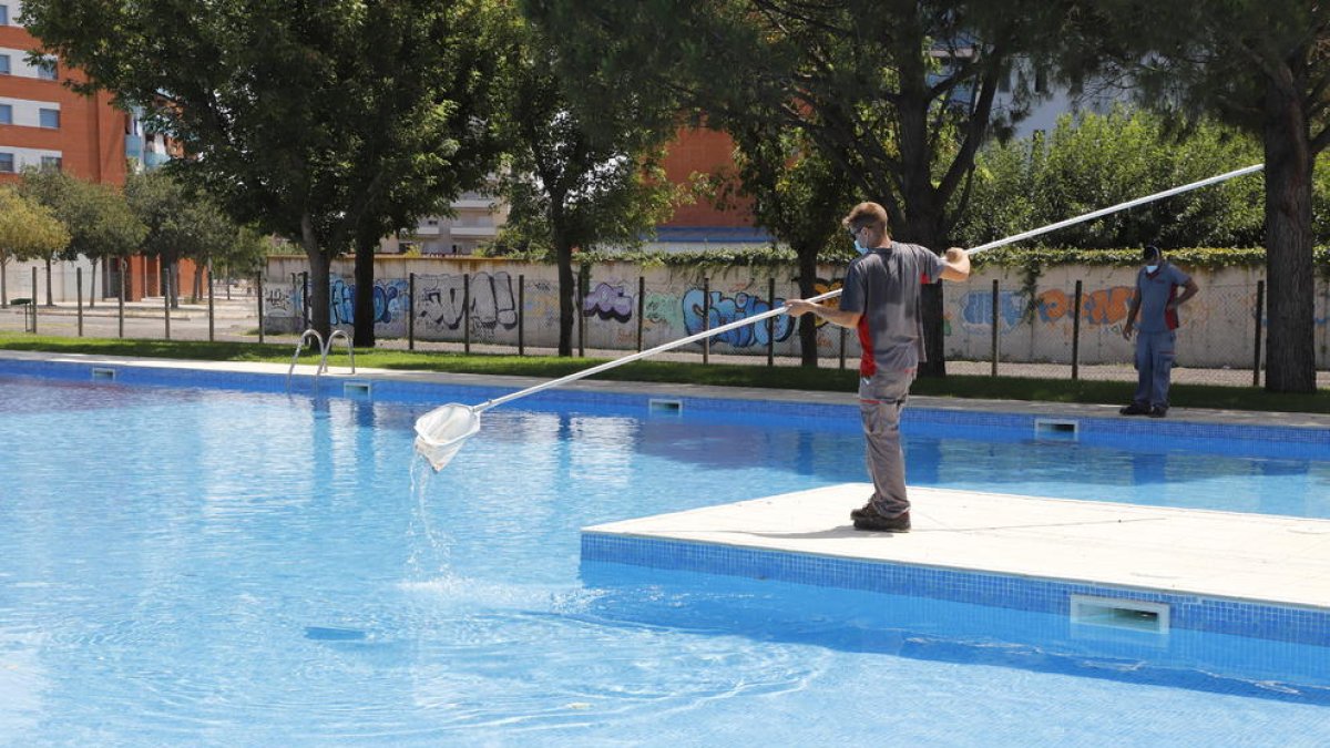 Operarios efectuando ayer tareas de limpieza en las piscinas municipales de Balàfia.