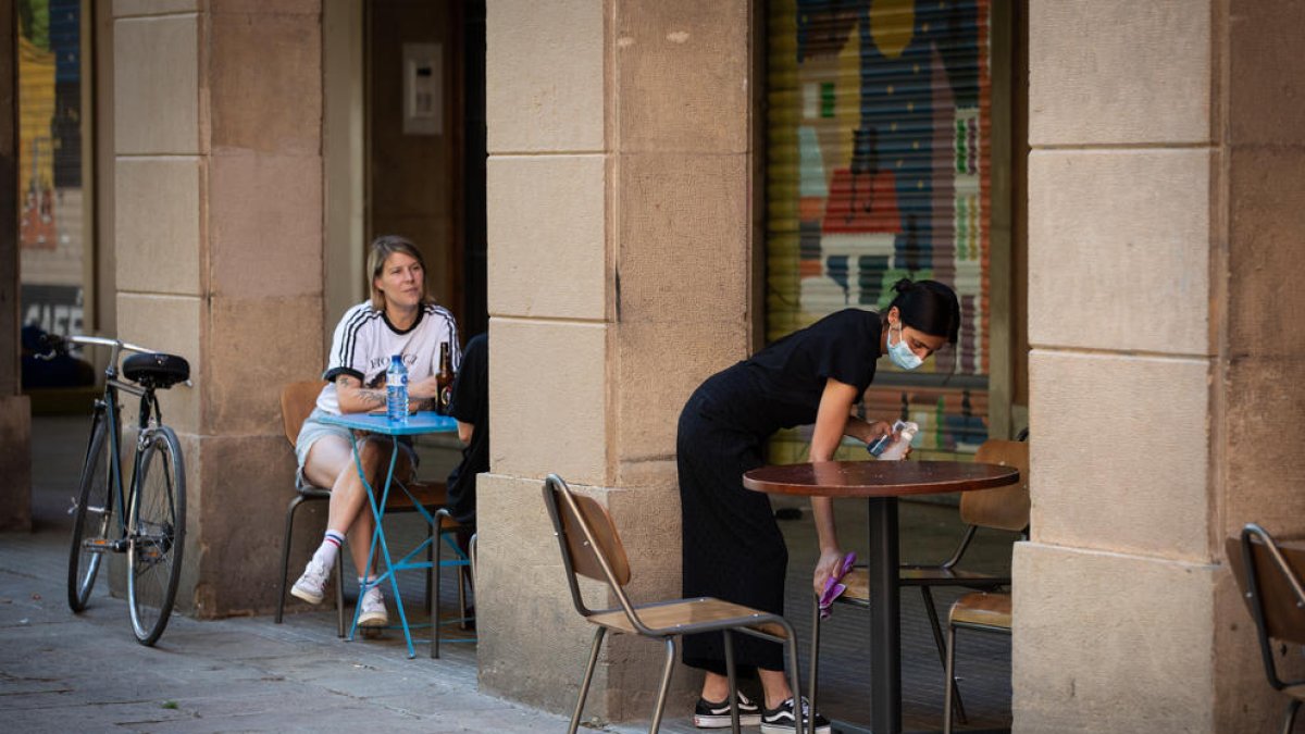 Una camarera desinfecta las mesas y las sillas de en un bar de Barcelona.