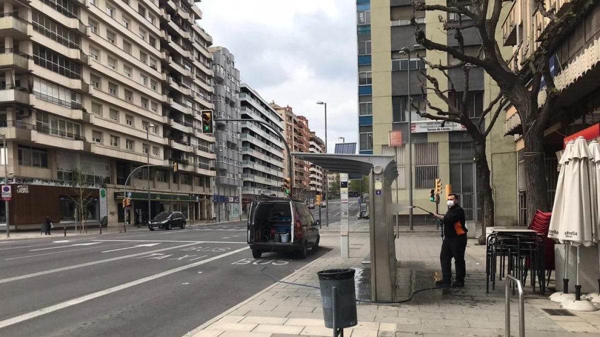 Un operari netejant una parada d’autobús a l’avinguda Catalunya, ahir al migdia.