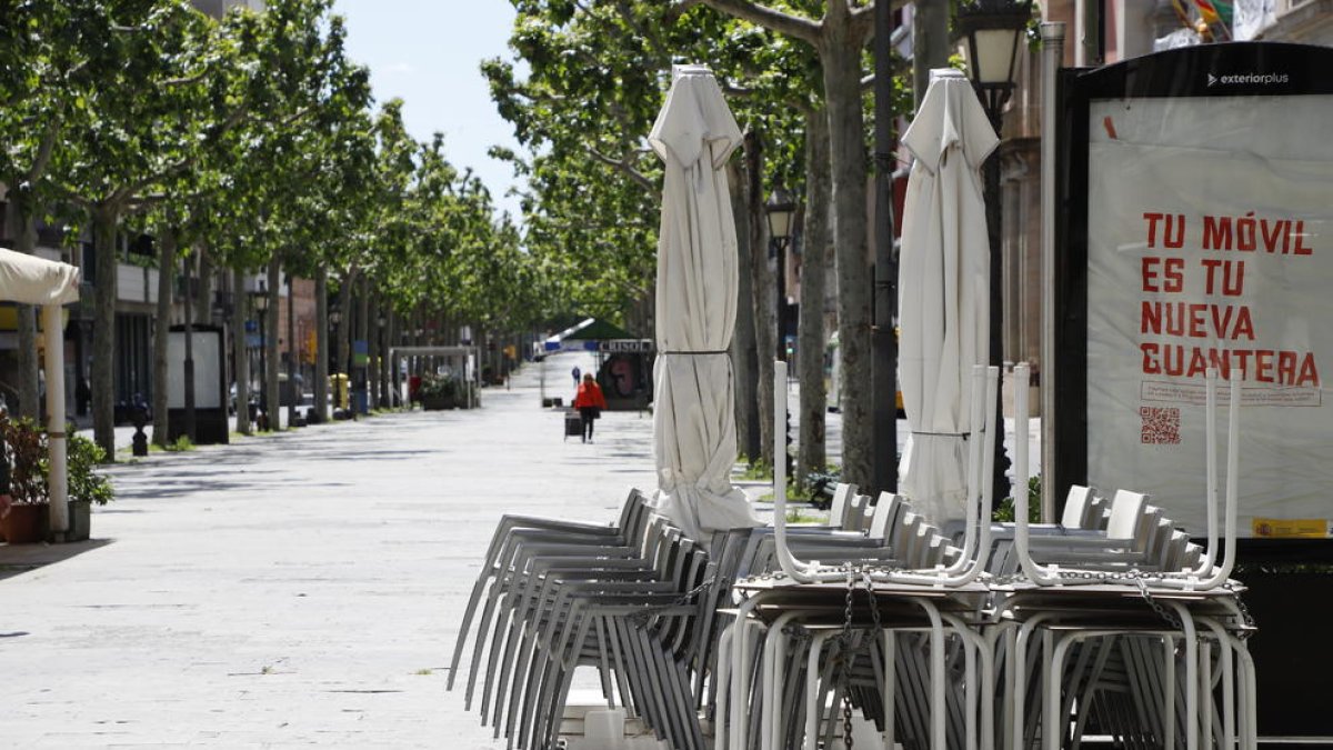 Sillas y mesas de la terraza de un bar apiladas en la Rambla Ferran de Lleida.