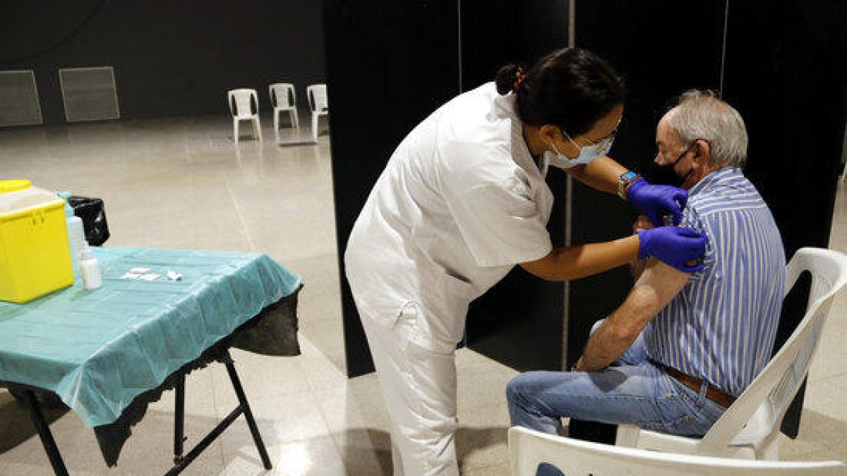 Una enfermera y un hombre a quien le acaban de administrar la vacuna de la gripe en el Espai MerCat de Tàrrega.