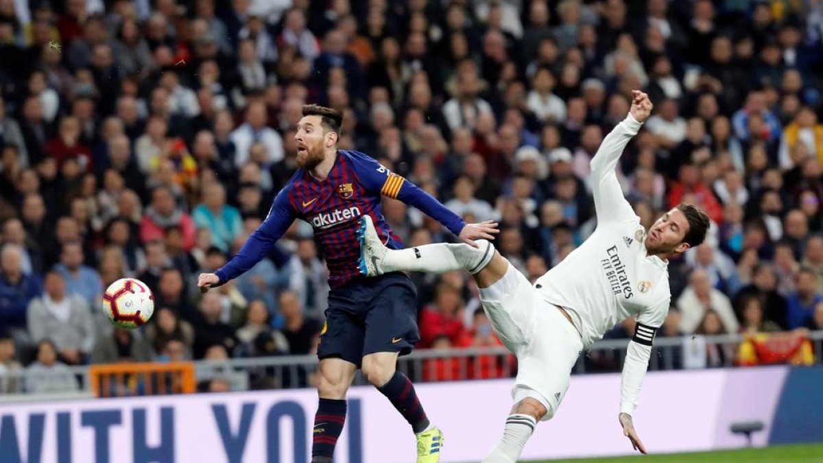 Messi rep una dura entrada de Sergio Ramos durant la disputa d’un clàssic.