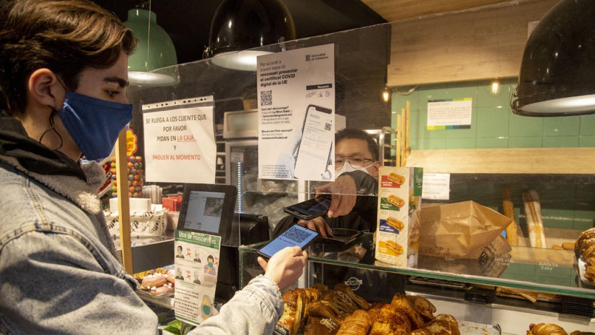 Un bar de Lleida, con carteles que indican la obligación del certificado, comprobando el de un cliente.