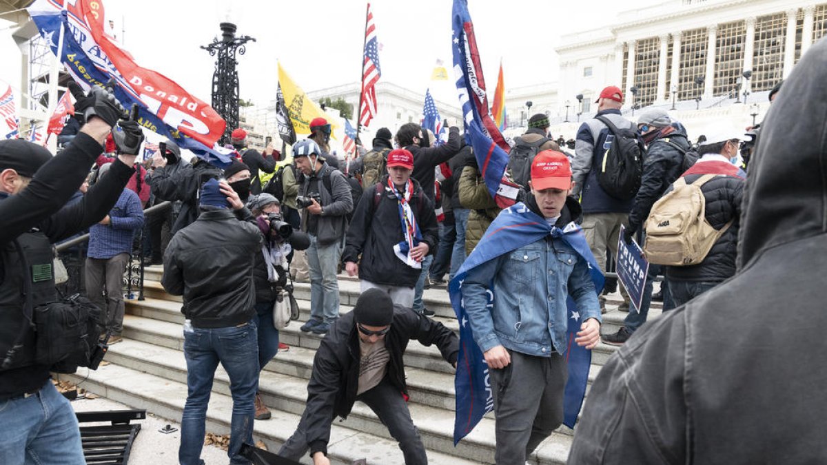 Los manifestantes derribando las vallas que rodeaban el Capitolio antes de irrumpir en él.