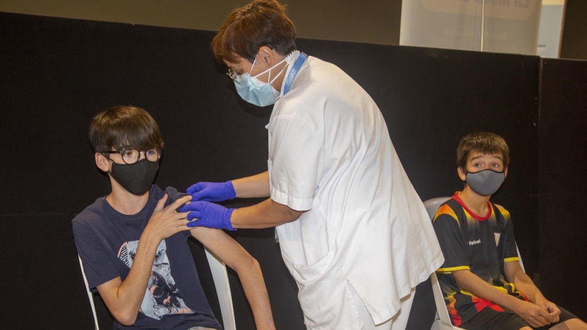 Un niño recibe la vacuna en Tàrrega mientras otro espera.