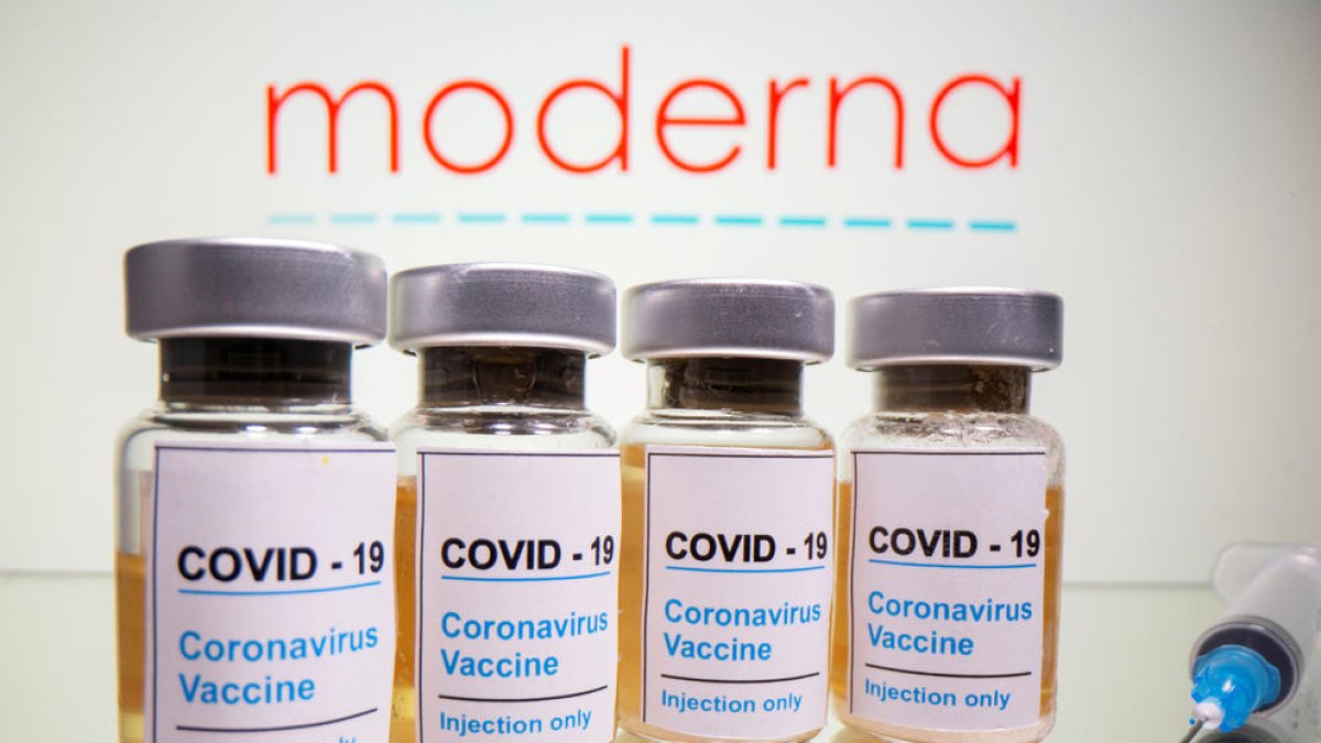 Viales con un adhesivo que dice 'COVID-19 / Vacuna contra el coronavirus / sólo para inyección' y una jeringa ante el logotipo de Moderna