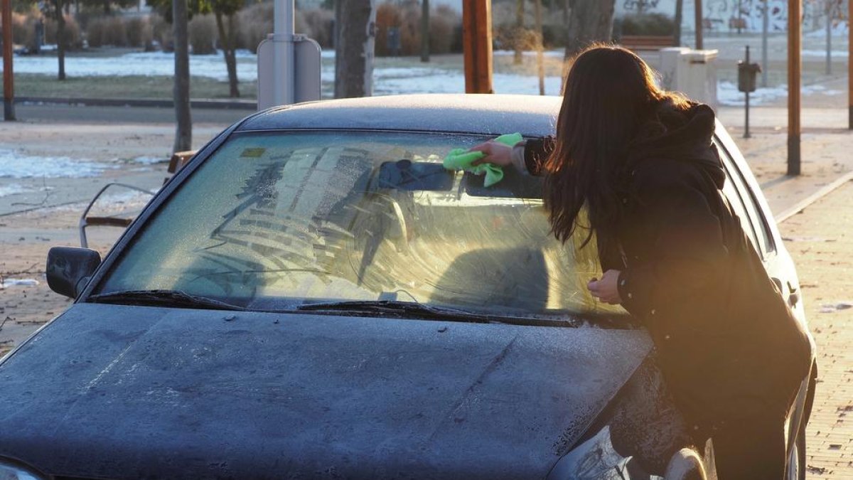 Una mujer retira el hielo de su vehículo