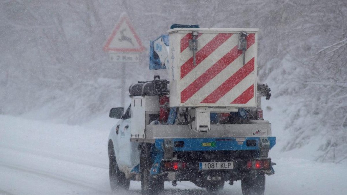 Un vehículo de trabajo para el mantenimiento de la red eléctrica circula en la carretera en plena helada.