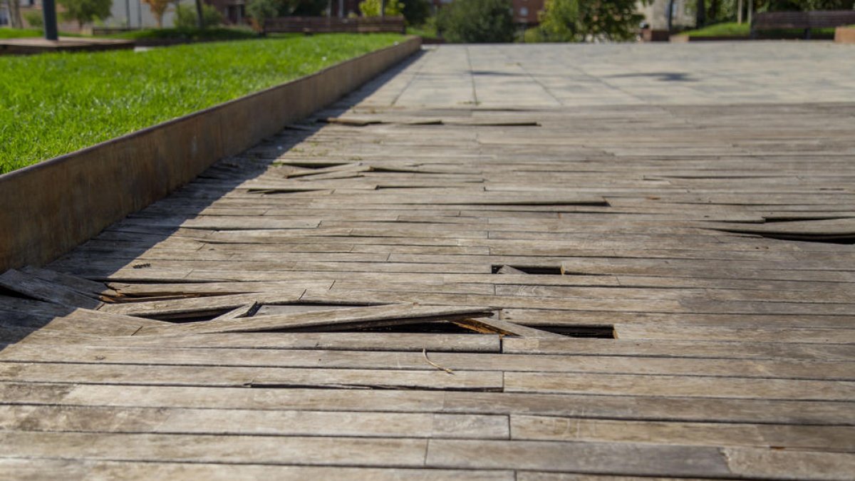 Imagen del pavimento de madera del cubrimiento de las vías, con muchas láminas levantadas.