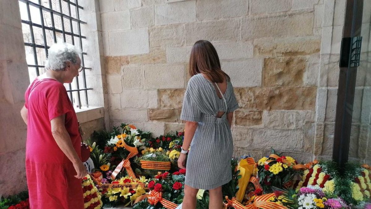 Dos mujeres contemplan las flores de las ofrendas en el Roser.